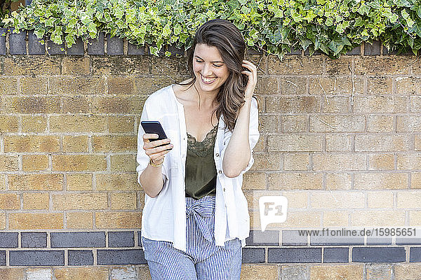 Lächelndes Frauenporträt mit Smartphone in der Hand
