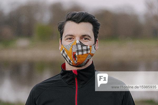 Porträt eines selbstbewussten jungen Mannes mit Gesichtsmaske im Park während des Coronavirus