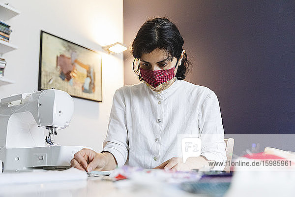 Selbstbewusste Frau  die während des Coronavirus eine selbstgemachte Gesichtsmaske anfertigt