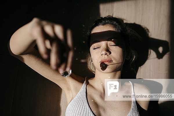Directly above view of young woman with pendant shadow on her face while lying down at home