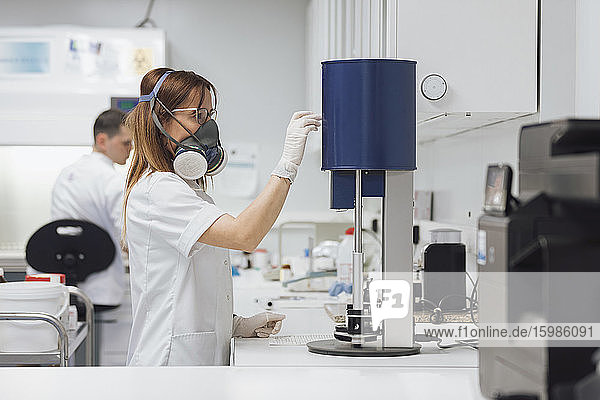 Weiblicher Techniker benutzt medizinische Geräte  während ein männlicher Kollege im Labor arbeitet