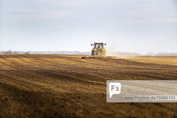 Farmer in tractor plowing field in spring