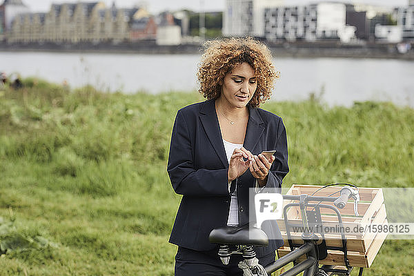 Geschäftsfrau mit Smartphone am Flussufer in Köln  Deutschland