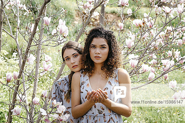 Verliebte Schwestern inmitten von Blumen im Park im Frühling