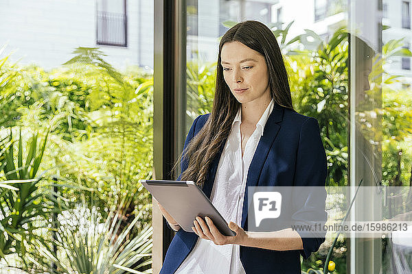 Geschäftsfrau mit Tablet an Glasscheibe