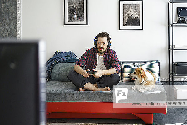Mann sitzt auf der Couch und spielt ein Videospiel