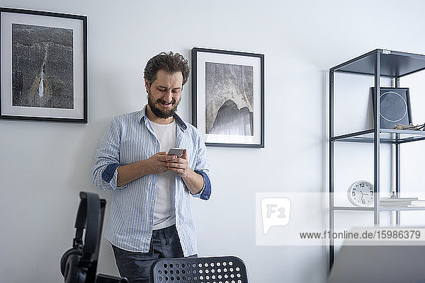 Smiling man using smartphone at home