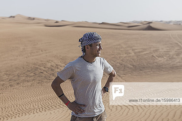 Männlicher Tourist schaut weg  während er auf Sanddünen in der Wüste von Dubai  Vereinigte Arabische Emirate  steht