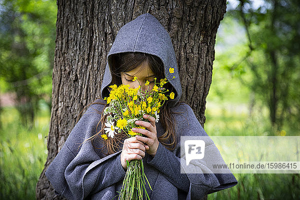 Girl smelling on bunch of yellow wildflowers