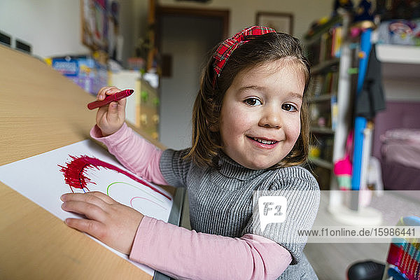 Porträt von lächelnden niedlichen Mädchen Färbung auf Papier zu Hause