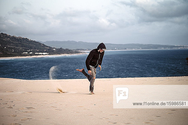 Junger Mann springt am Strand gegen den Himmel in Tarifa  Spanien