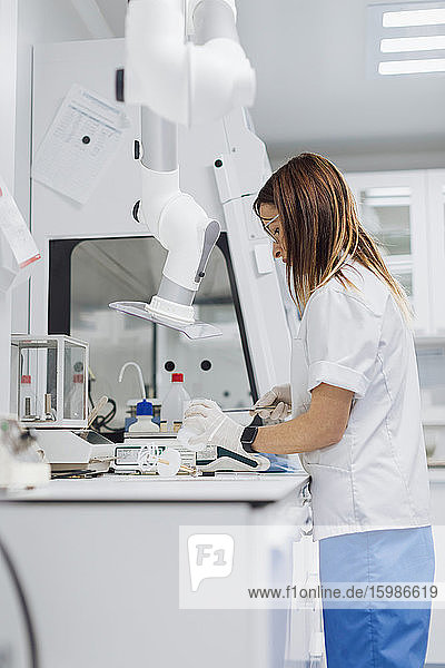 Confident female healthcare worker standing at desk in lab