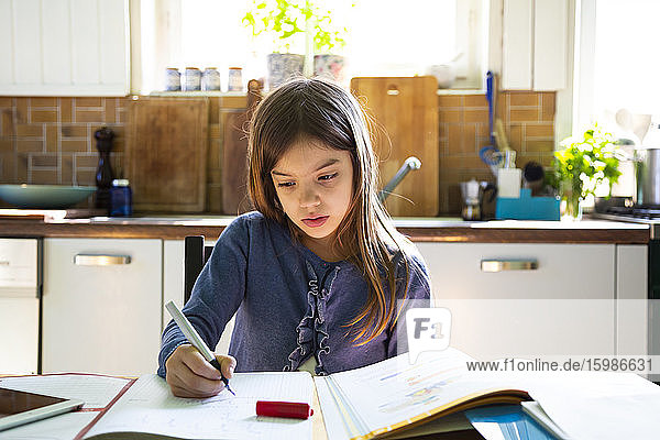 Mädchen macht Hausaufgaben in der Küche zu Hause