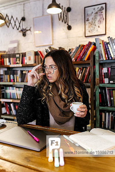 Frau schreibt in einem Café in ein Notizbuch