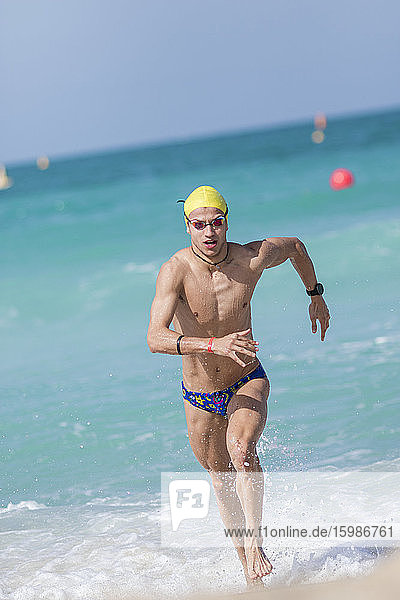 Männlicher Schwimmer  der am Strand von Dubai  Vereinigte Arabische Emirate  ans Ufer läuft