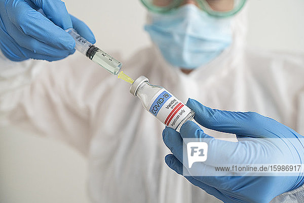 Frau in Schutzkleidung bei der Vorbereitung der Covid-19-Impfung