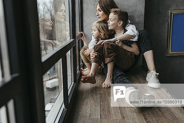 Familie in voller Länge beim Blick durch das Fenster zu Hause