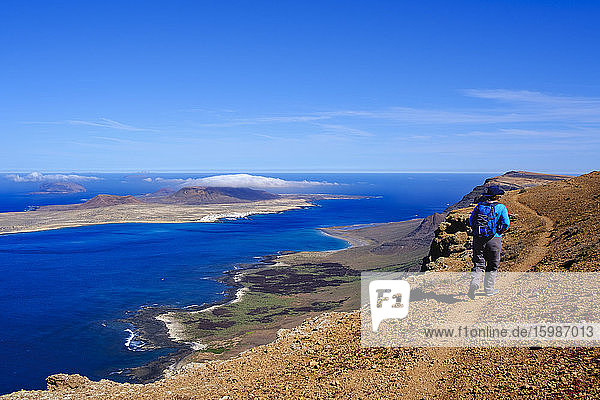 Spain  Canary Islands  Female backpacker hiking along edge of coastal cliff of La Graciosa island