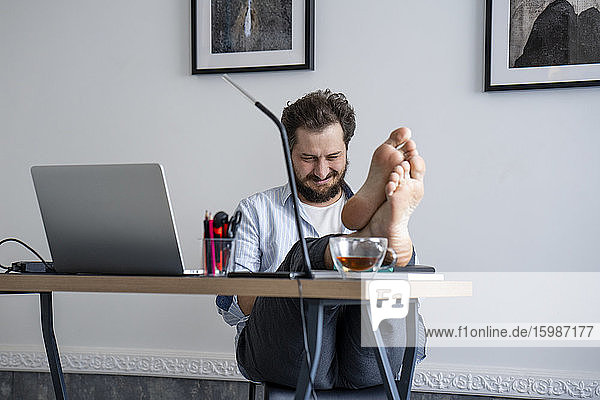 Mann sitzt am Schreibtisch  Füße hochgelegt