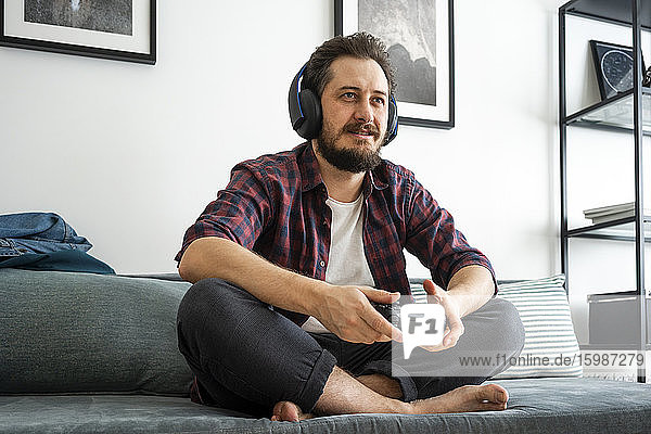 Mann sitzt auf der Couch und spielt ein Videospiel