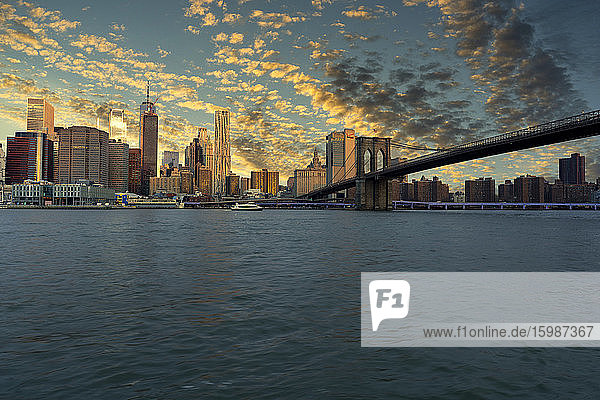 USA  New York  New York City  East River und Brooklyn Bridge bei dramatischem Sonnenaufgang mit der Skyline von Manhattan im Hintergrund