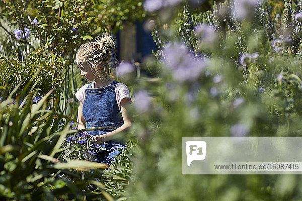 Girl wearing daisy flower wreath in allotment garden
