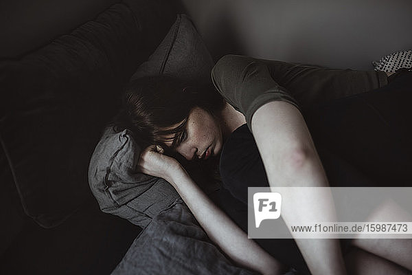 Depressed young woman lying on bed