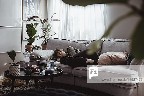 Worried young woman lying on sofa at home