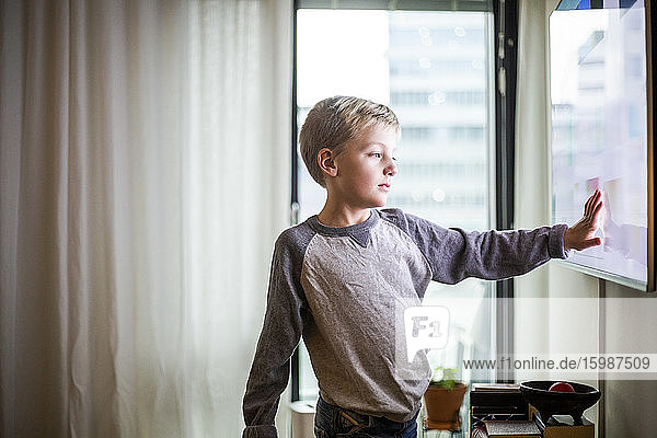 Junge berühren Bildschirm des Smart TV im modernen Zuhause