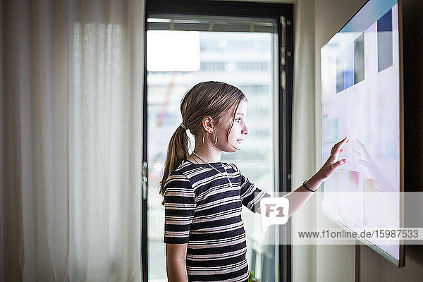 Mädchen berühren digitalen Bildschirm von Smart TV im modernen Zuhause