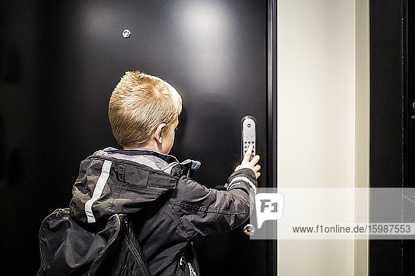 Boy unlocking combination security code on house door