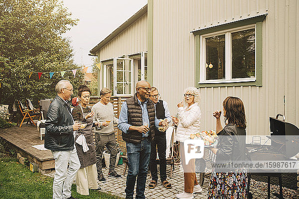 Aktive ältere Männer und Frauen genießen Dinnerparty im Hinterhof