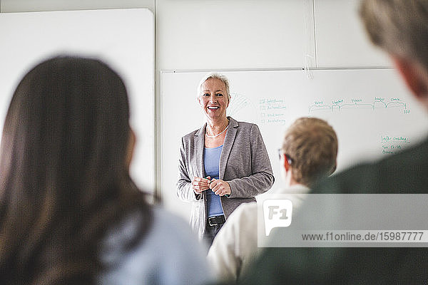 Lächelnde reife Lehrerin lehrt im Universitäts-Klassenzimmer