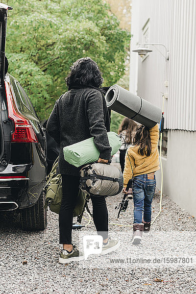 Familie entlädt Gepäck aus Elektroauto