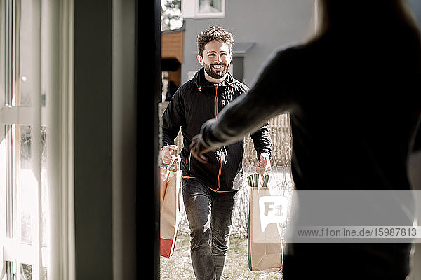 Smiling young delivery man delivering grocery to female customer at home