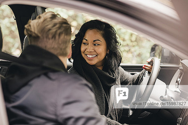 Lächelnde Frau schaut zurück  während sie Elektroauto fährt