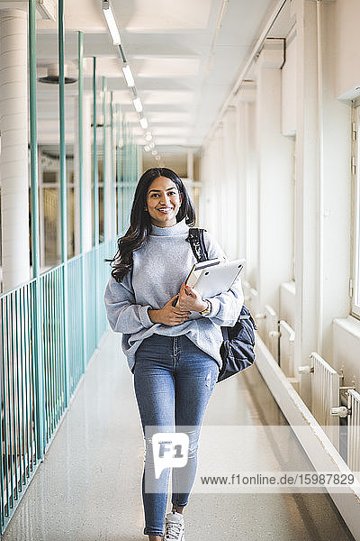 Porträt einer jungen Studentin  die im Korridor der Universität geht