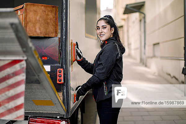 Seitenansicht Porträt einer jungen Lieferfrau mit Lastwagen in der Stadt