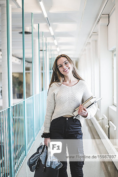 Porträt einer lächelnden jungen Studentin im Korridor der Universität