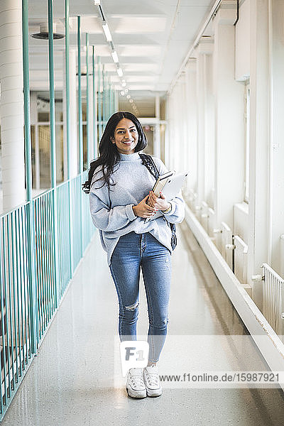 Porträt einer jungen Studentin  die im Korridor der Universität steht