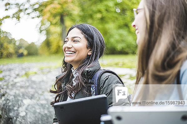 Lächelnde junge Frau mit Freundin auf dem Universitätscampus