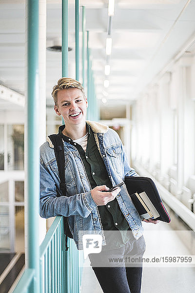 Portrait of smiling young male student in corridor of university