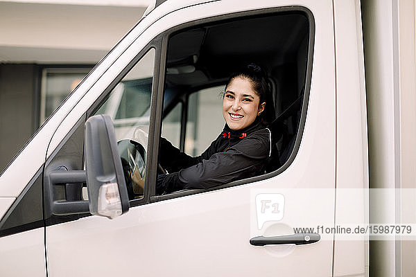 Zuversichtliche junge Lieferfrau am Steuer eines Lastwagens