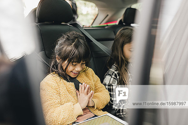 Lächelndes Mädchen benutzt digitales Tablet  während es im Auto sitzt