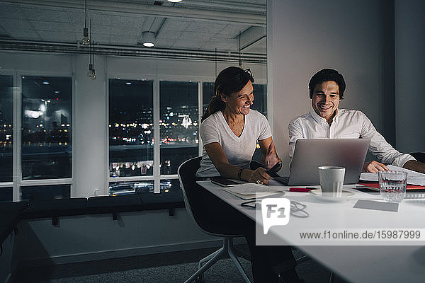 Lächelnder Geschäftsmann und Geschäftsfrau planen Strategie  während sie im Büro auf den Laptop schauen