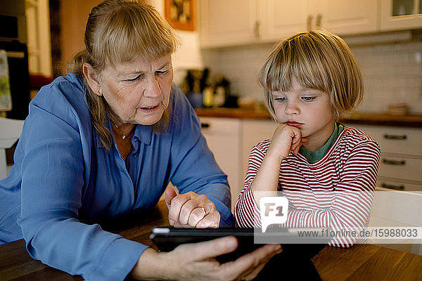 Boy looking at grandmother using digital tablet