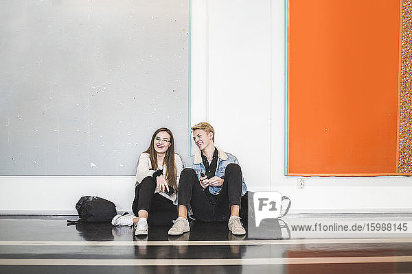 Junger Mann sitzt mit Freundin auf dem Flur der Universität
