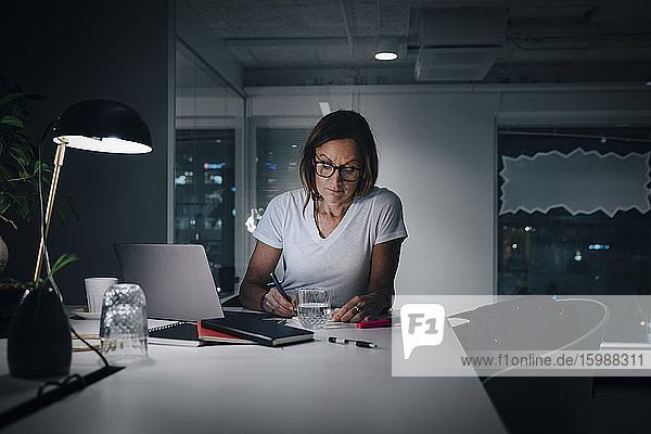 Weibliche Berufstätige  die spät arbeiten  während sie im Büro am Schreibtisch sitzen