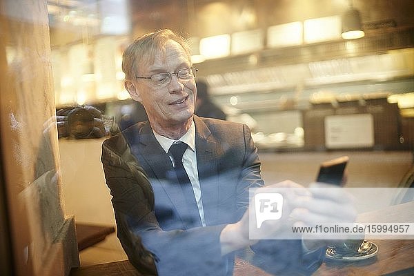 Businessman using smartphone in cafe in London UK.