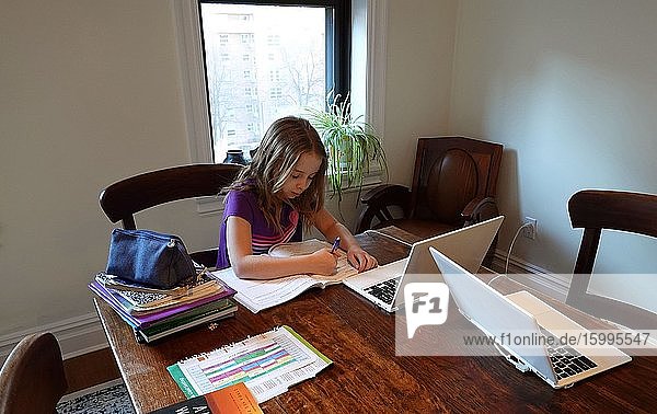Schoolgirl using a laptop working on a table from home during the Coronavirus lockdown New York NY.